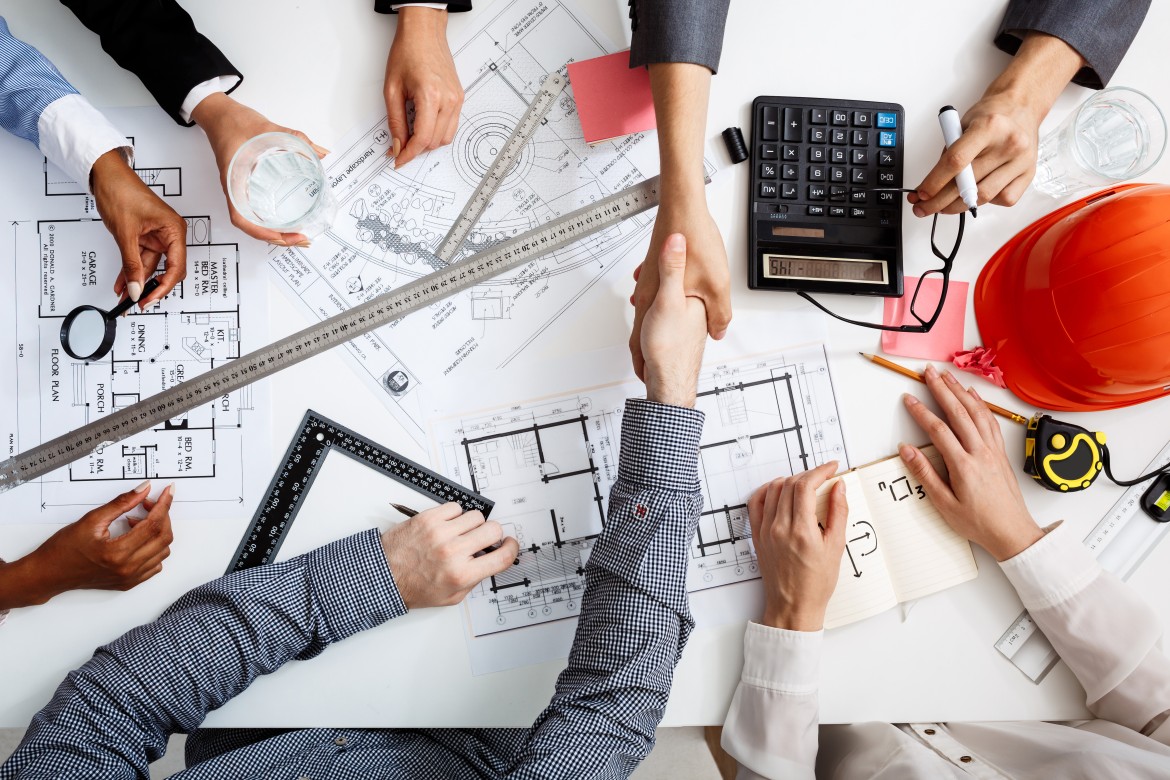 Construction professionals collaborating over blueprints and cost estimates to address the construction skill gap